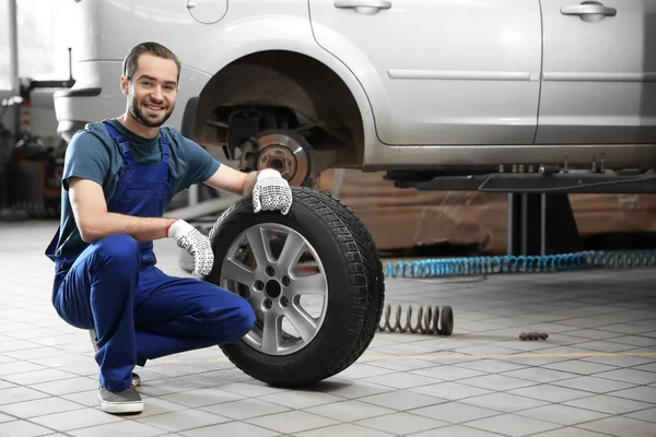 서비스 센터에서 자동차 타이어를 다루는 젊은 기계공 — 스톡 사진