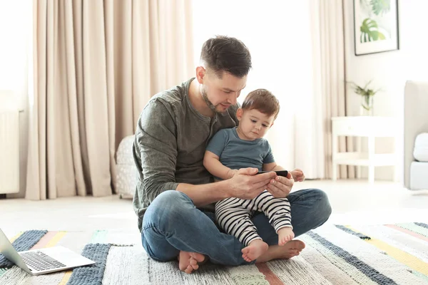 Тато і його син з телефону на килим на дому — стокове фото