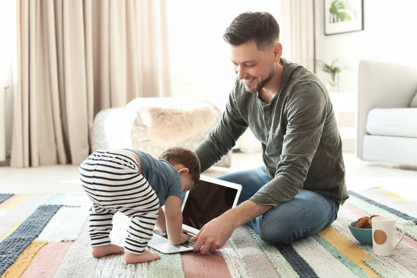 Тато і його син з ноутбука на килим на дому — стокове фото
