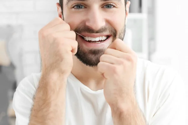 Jeune homme fil dentaire à l'intérieur — Photo