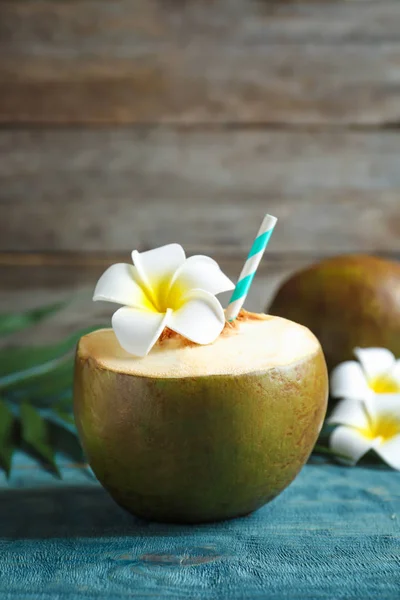 Čerstvý zelený kokos s pitím slámy na dřevěný stůl — Stock fotografie