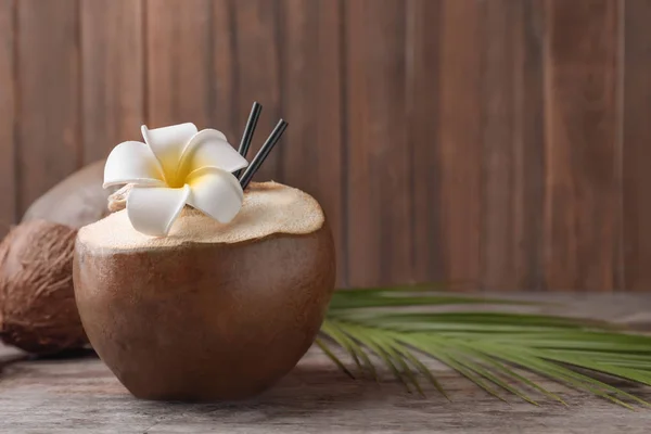 Verse groene kokosnoot op tafel tegen houten achtergrond — Stockfoto