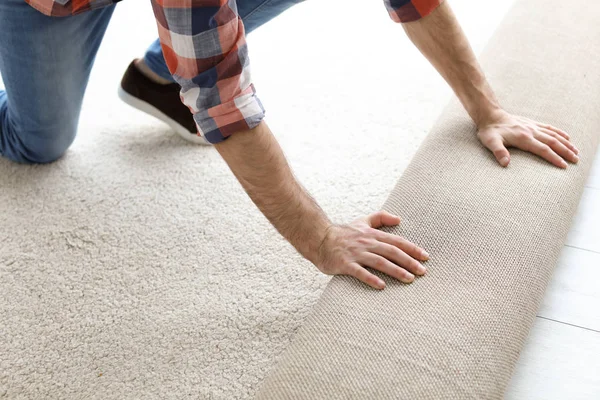 Hombre rodando nuevo suelo de alfombra en la habitación —  Fotos de Stock