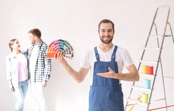 Decorador masculino com paleta de cores e casal desfocado no fundo branco — Fotografia de Stock