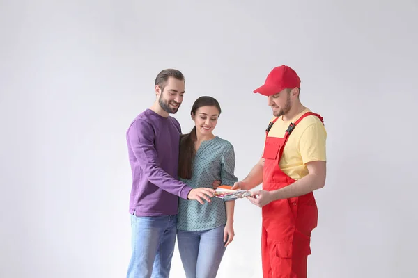 Männlicher Dekorateur und junges Paar mit Farbpalette auf weißem Hintergrund — Stockfoto