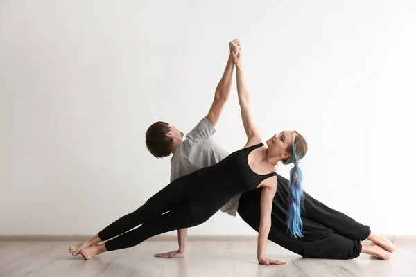 Joven hombre y mujer practicando yoga en interiores — Foto de Stock
