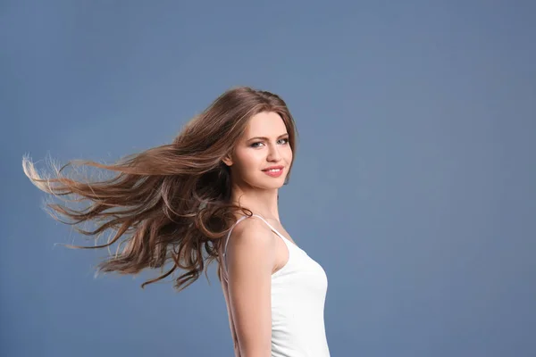 Портрет молодої жінки з довгим красивим волоссям на сірому фоні — стокове фото