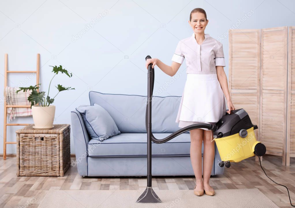 Young woman hoovering carpet with vacuum cleaner in living room