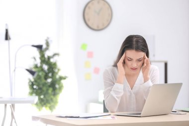 Ofiste baş ağrısı çeken genç bir kadın.