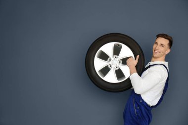 Gri arka plan üzerinde otomobil lastiği ile erkek makinist
