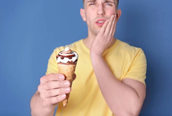 Junger Mann mit empfindlichen Zähnen und kaltem Eis auf farbigem Hintergrund — Stockfoto