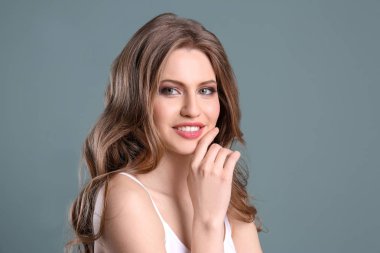 Gri arka plan üzerinde uzun güzel saçlı genç kadın portresi