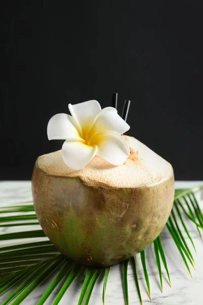 Verse groene kokosnoot op tafel tegen de donkere achtergrond — Stockfoto