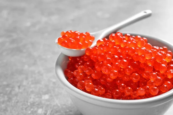 Cuenco de cerámica y cuchara con delicioso caviar rojo en la mesa, primer plano —  Fotos de Stock