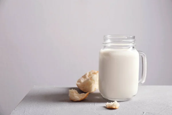 Tarro Mason con leche y bollos en la mesa contra la pared gris —  Fotos de Stock