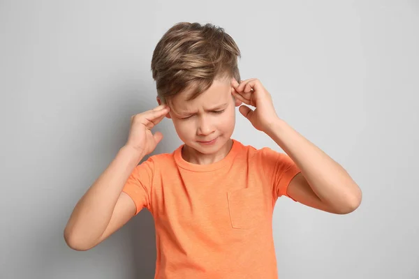 Niño que sufre de dolor de cabeza sobre fondo gris — Foto de Stock