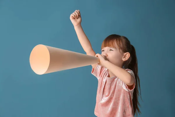 Милая маленькая девочка с бумажным мегафоном на цветном фоне — стоковое фото