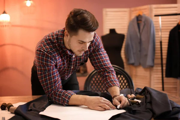 Joven sastre trabajando con patrón de costura en atelier — Foto de Stock