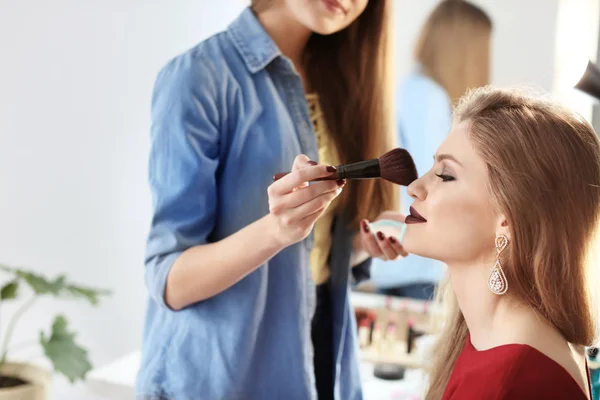 专业化妆艺术家与美丽的年轻女子工作室 — 图库照片
