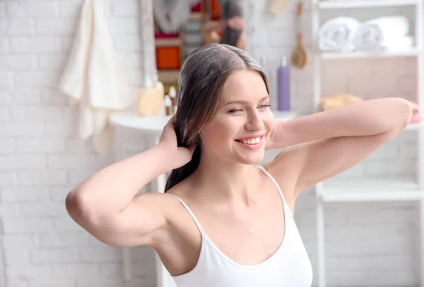 Mujer joven aplicando máscara en el cabello en casa — Foto de Stock