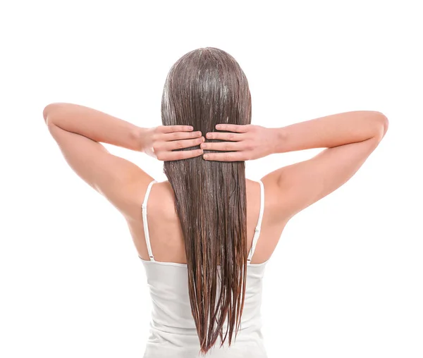 Jovem mulher aplicando máscara no cabelo contra fundo branco — Fotografia de Stock