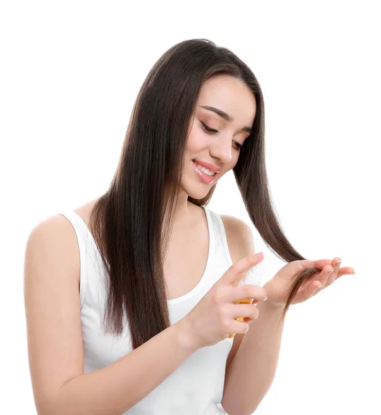 Молодая женщина наносит масло на волосы на белом фоне — стоковое фото
