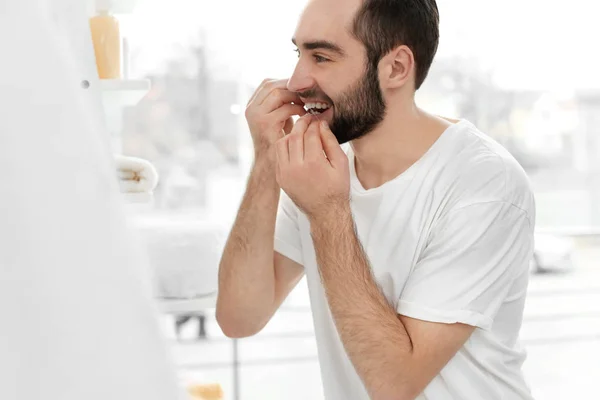 Young man flossing his teeth indoors — Stock Photo, Image