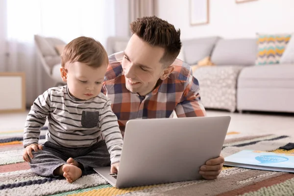 Jonge vader met zijn schattige zoontje met behulp van laptop thuis — Stockfoto