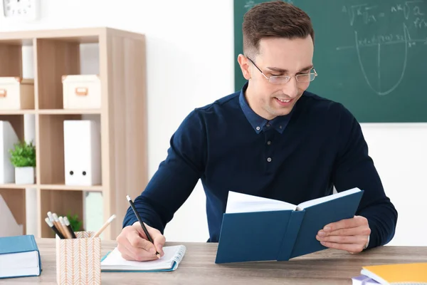 Ung manlig lärare arbetar vid bord i klassrummet — Stockfoto