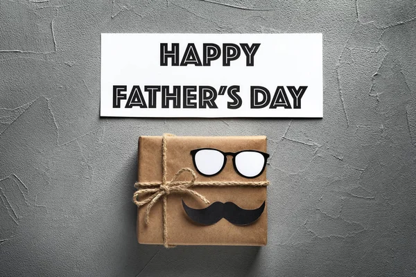 Gift box with paper glasses and moustache on grey background, top view. Father's day celebration — Stock Photo, Image