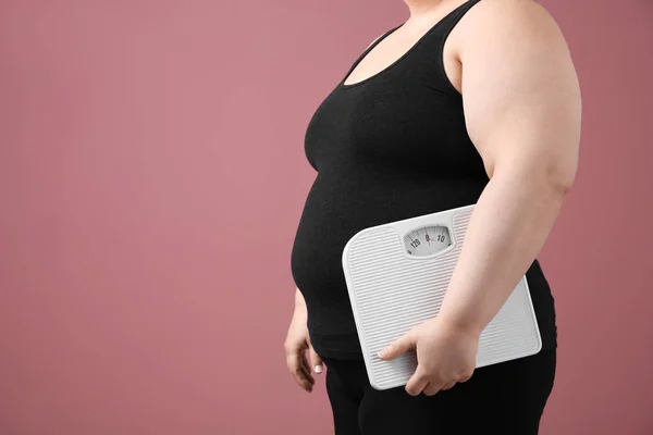 Overgewicht vrouw met schubben op kleur achtergrond — Stockfoto