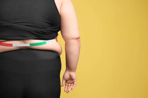 Mulher com excesso de peso com fita métrica no fundo de cor — Fotografia de Stock