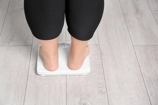 Mulher com excesso de peso usando escalas dentro de casa — Fotografia de Stock