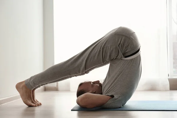 Homem desportivo praticando ioga dentro de casa — Fotografia de Stock