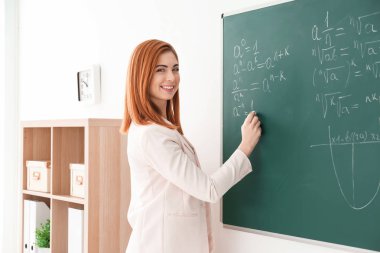 Güzel genç öğretmen sınıfta yazı tahtası üzerinde yazma