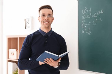 Genç erkek öğretmen sınıfta kitap ayakta ile