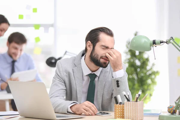 Молодий чоловік страждає від головного болю в офісі — стокове фото