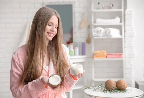 Jonge vrouw met kokosolie voor haar in de badkamer — Stockfoto