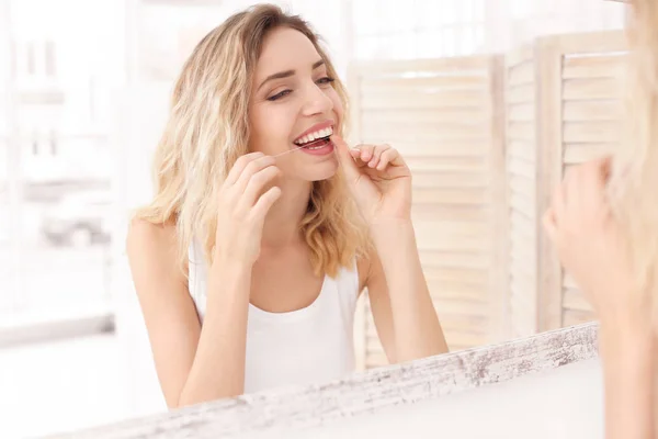 年轻妇女在洗手间用牙线刷牙 — 图库照片