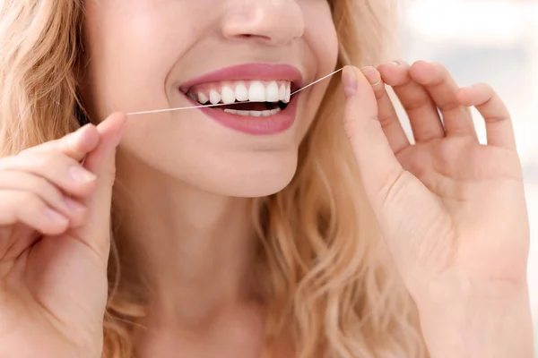 Mujer joven usando hilo dental, primer plano — Foto de Stock