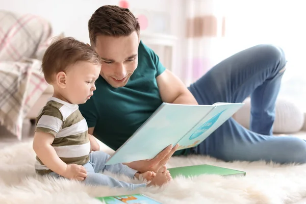 Jovem pai lendo livro com seu filho bonito em casa — Fotografia de Stock