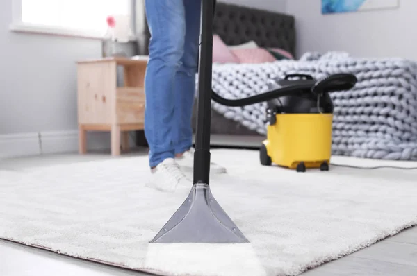 Mature man hoovering carpet with vacuum cleaner at home — Stock Photo, Image