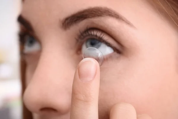 Молодая женщина кладет контактные линзы в глаз, крупным планом — стоковое фото