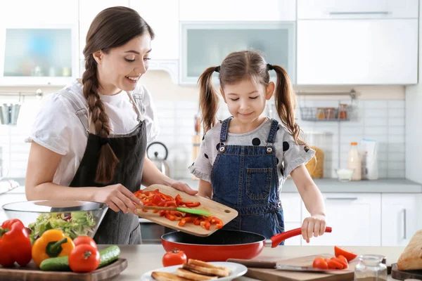 Молодая няня с милой маленькой девочкой готовит вместе на кухне — стоковое фото