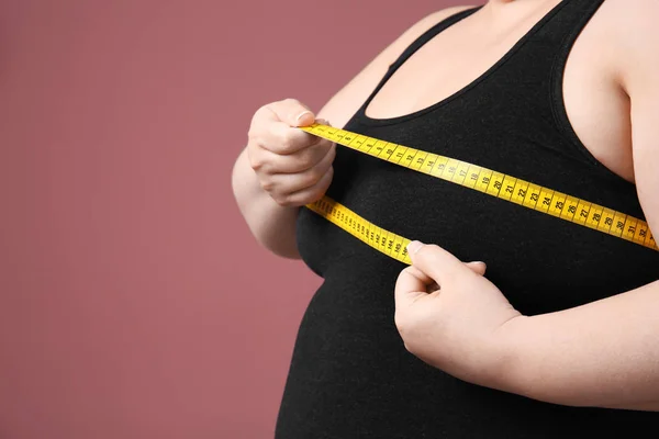 Overweight woman with measuring tape on color background — Stock Photo, Image