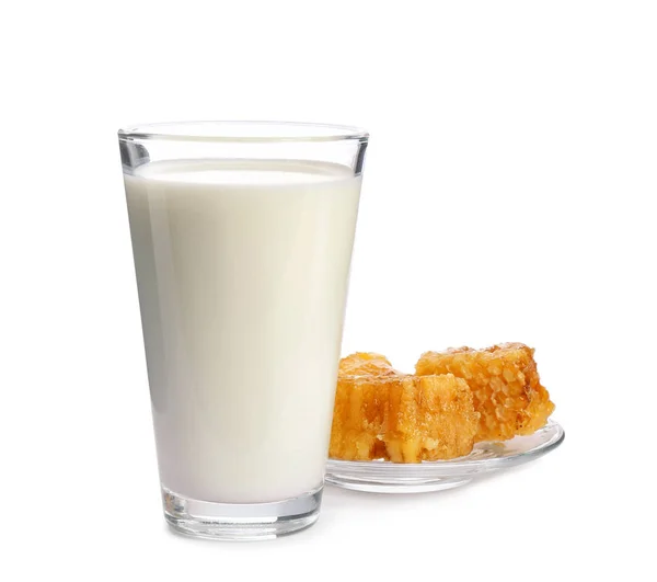 Vidro com leite e favos de mel no fundo branco — Fotografia de Stock
