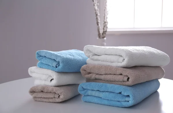 Pilhas de toalhas limpas na mesa dentro de casa — Fotografia de Stock