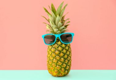 Renk arka plan üzerinde güneş gözlüklü olgun taze ananas