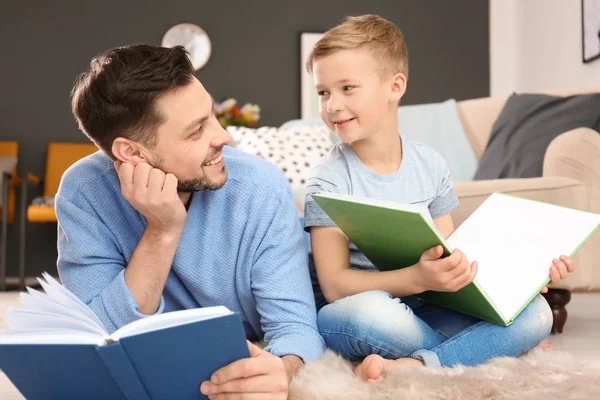Маленький мальчик и его отец читают дома книги — стоковое фото