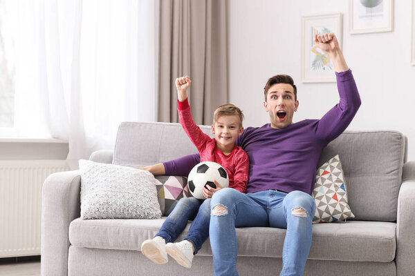 Dad and his son watching football at home